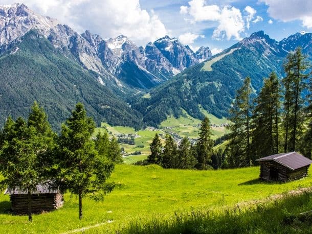 Almwiese mit Heustadel vor bewaldeten Hängen im Stubaital