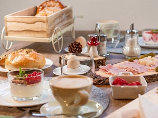 Gedeckter Frühstückstisch mit Gebäck, Aufschnitt und Kaffee