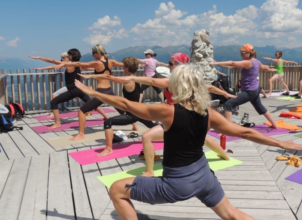 Yogagruppe auf einer Terrasse vor den Bergen