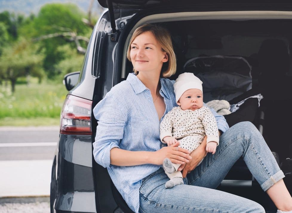 Mutter mit Baby bei der Anreise am Auto