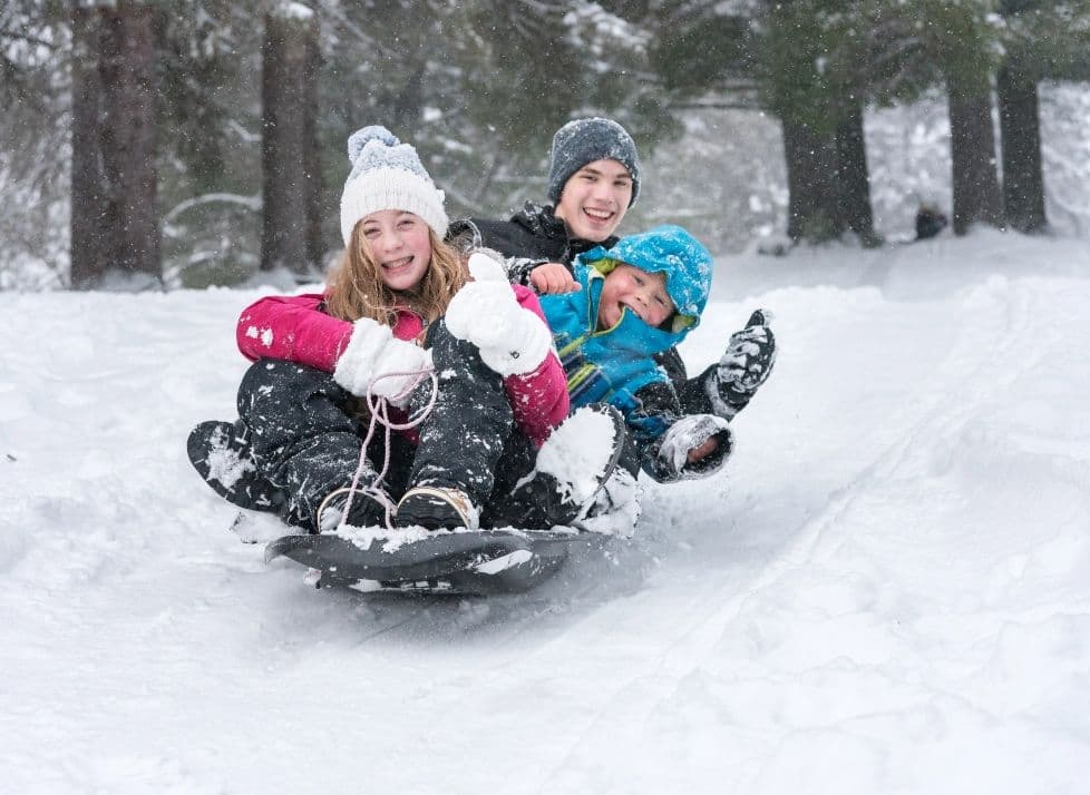 Kinder auf einer Rodel im Schnee